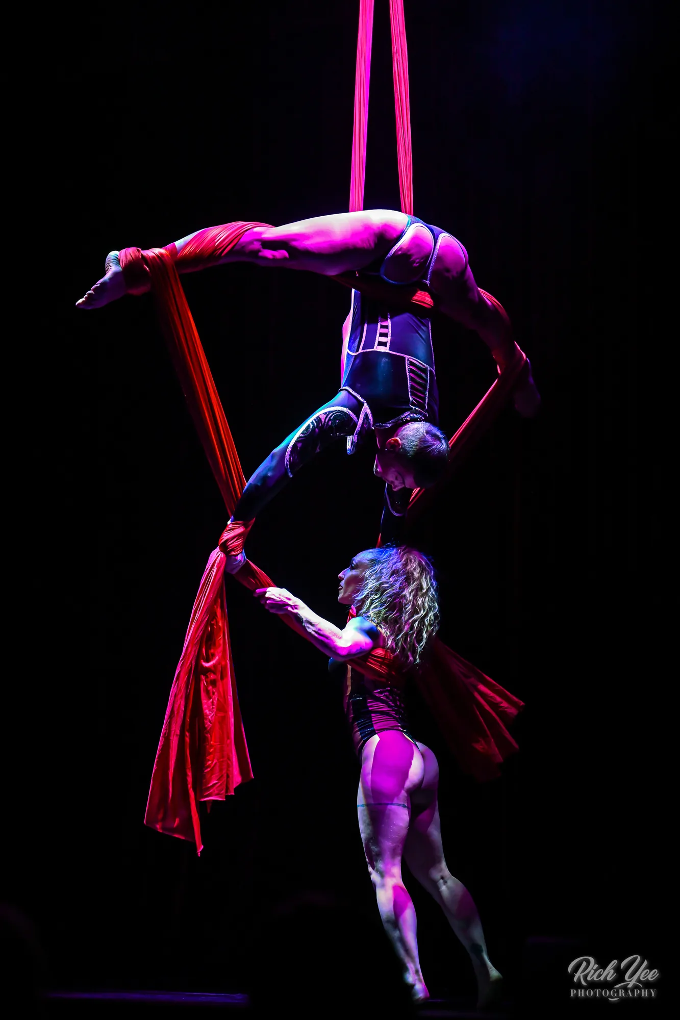 Duo aerial silks hand-to-hand in red light