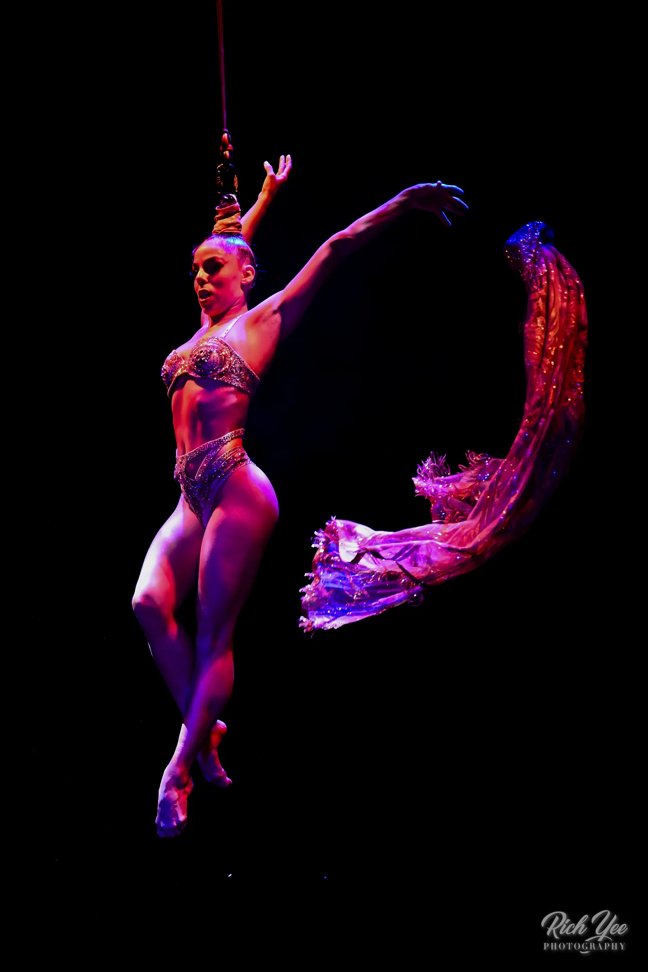 Hair-hang aerialist with sequined cape in motion
